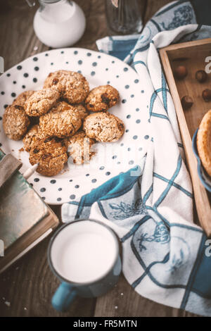 Book, pitcher, oatmeal cookies and a cup of milk on old boards vertical Stock Photo