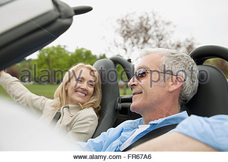 middle-aged couple driving in a convertible