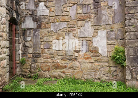 Wall built with broken tombstones with Latin inscriptions Stock Photo