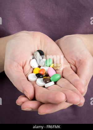 Closeup of white female hands holding all sorts of pills and tablets Stock Photo