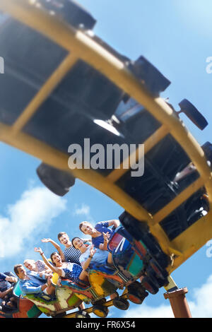 Friends riding roller coaster at sunny amusement park Stock Photo