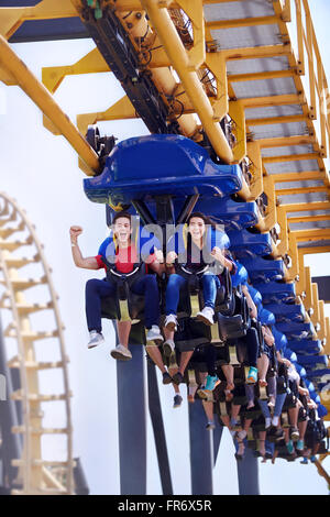 Young man cheering on amusement park ride Stock Photo