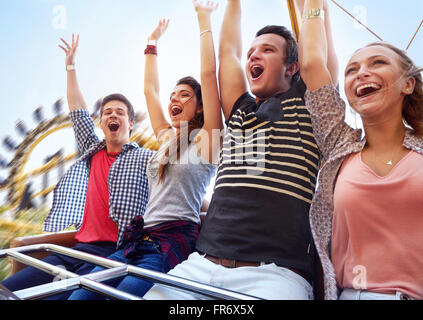 Cheering friends riding amusement park ride Stock Photo