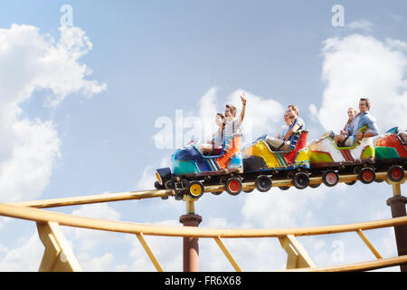 Friends cheering riding roller coaster at amusement park Stock Photo