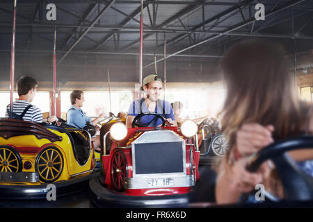 Young man riding bumper cars at amusement park Stock Photo