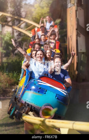 Portrait enthusiastic friends cheering and riding roller coaster at amusement park Stock Photo