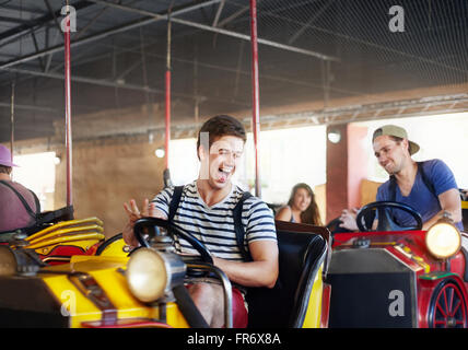 Laughing young men riding bumper cars at amusement park Stock Photo