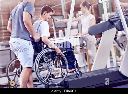 Physical therapists guiding man in wheelchair on treadmill Stock Photo