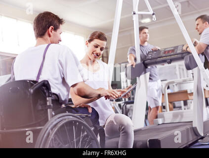 Physical therapist showing digital tablet to man in wheelchair Stock Photo