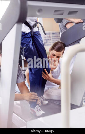 Physical therapists guiding man on treadmill Stock Photo