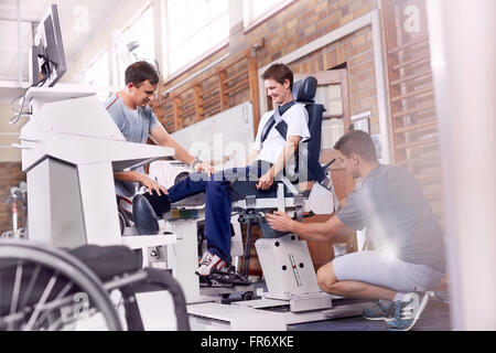 Physical therapists guiding man using equipment Stock Photo