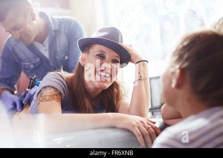 Smiling woman getting a back tattoo Stock Photo