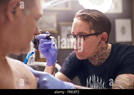 Focused tattoo artist preparing tattoo gun Stock Photo