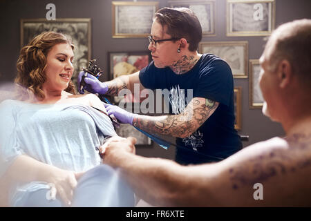 Tattoo artist tattooing woman’s shoulder Stock Photo