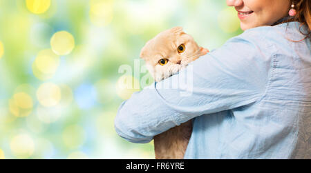 happy woman holding scottish fold cat over green Stock Photo