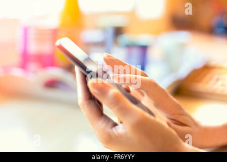 Morning breakfast, Woman in her kitchen texting a Message on smart phone. Lens flare Stock Photo