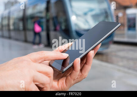 Female using her cell phone on platform station tramway Stock Photo