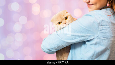 woman holding scottish fold cat over pink lights Stock Photo