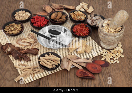 Moxa sticks and chinese herbs used in traditional herbal medicine with mortar and pestle over bamboo and oak background. Stock Photo