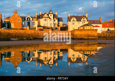 20/03/2016, The sun sets on a row of houses reflected in the water at Elie, a coastal town in the East Neuk of Fife, Scotland. Stock Photo