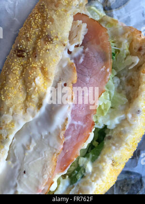 Closeup of a submarine sandwich with chicken, ham,lettuce,spinach, cheese and mayonnaise on multi-grain bread. Stock Photo