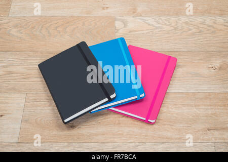 Brightly colored note books arranged pleasingly on a wooden background Stock Photo