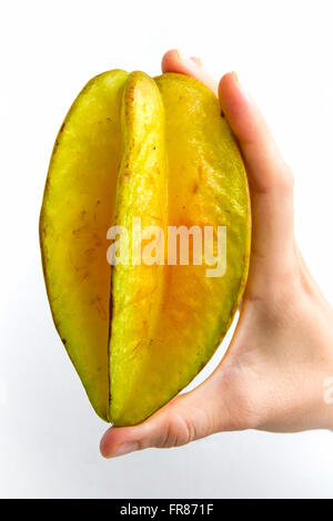 A carambola, commonly known as starfruit, held upright in the hand of a young woman, isolated on white. Stock Photo