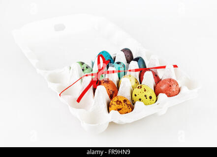Eco-friendly packaging with dyed Easter eggs, tied with a red satin ribbon. Painted quail eggs. Stock Photo