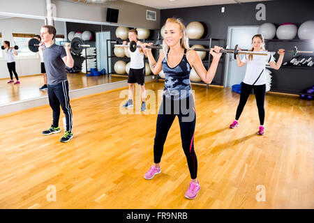 Smiling team doing squat exercises with weights at fitness gym Stock Photo
