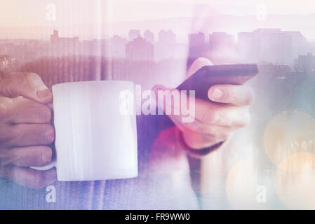 Casual man reading SMS text messages on his smartphone and drinking coffee in the morning, multilayered double exposure image Stock Photo