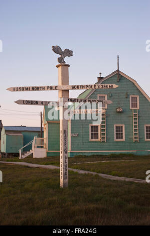 Drection sign post pointing to the North and South Pole with a residential building in the background, Barrow, North Slope, Arctic Alaska, Summer Stock Photo