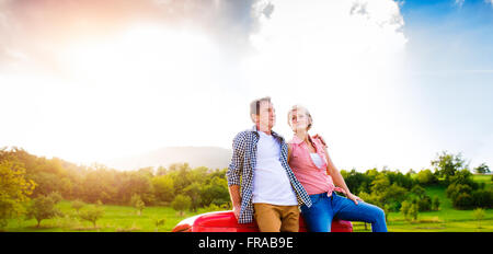 Senior couple sitting in back of red pickup truck Stock Photo