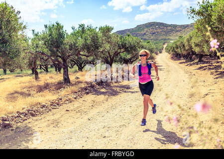 Trail runner woman cross country running on dirt road in mountains on summer beautiful day. Training and working out female jogg Stock Photo