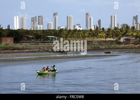 Boat on the River Island Capibaribe with God and building from Boa Viagem beach in the background Stock Photo