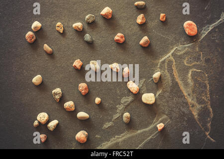 Vintage filtered stones on dark grunge slate background. Stock Photo