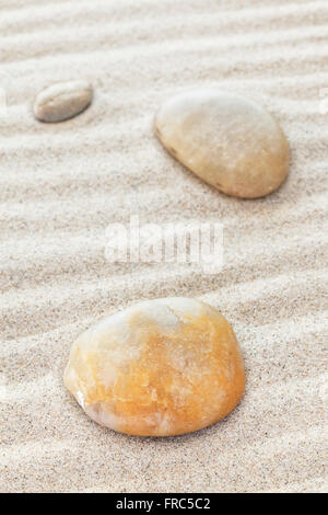 Stones on sandy waves, nature, harmony, zen or spa concept background, shallow depth of field. Stock Photo
