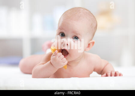 baby child lying on belly weared with teether in mouth Stock Photo