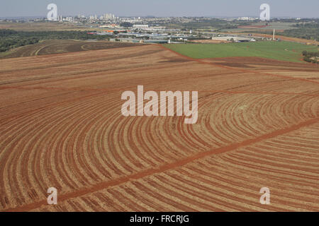 Aerial view of land plowed for planting cane sugar in the countryside - the background urban area Stock Photo