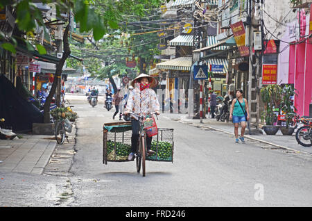 A lime seller rides down a street in the early morning, Hanoi, Vietnam Stock Photo