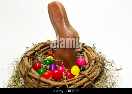 Chocolate Easter bunny in nest with colorful jelly beans. Stock Photo