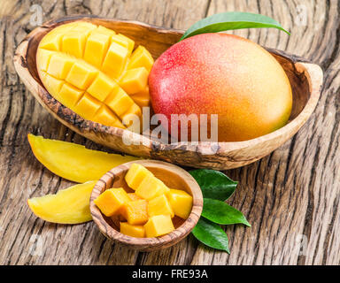 Mango fruit and mango cubes on the wooden table. Stock Photo