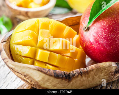 Mango fruit and mango cubes on the wooden table. Stock Photo