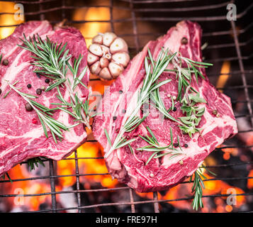 Rib eye steaks and grill with burning fire behind them. Stock Photo