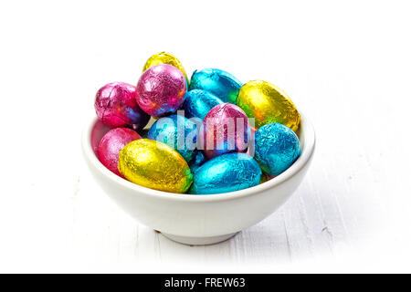 Chocolate eggs in bowl on wooden table Stock Photo