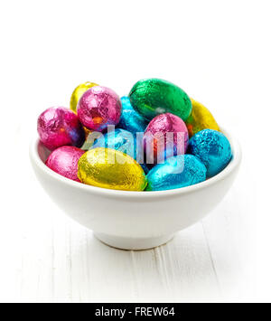 Chocolate eggs in bowl on wooden table Stock Photo