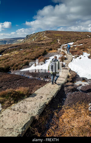 Men walking along stone slabs towards Crowden Tower on the Pennine way in the Peak District, Derbyshire, England, U.K. Stock Photo