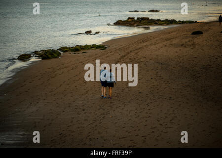 LAS PALMAS, GRAN CANARIA island, SPAIN - DECEMBER 1, 2015: Elder couple dressed alike in sport clothes walking the beach on the Stock Photo