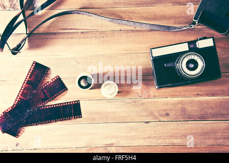Retro vintage camera and photographic film on wooden background. Instagram retro vintage picture. Stock Photo