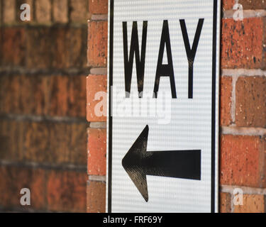 Sign with Arrow on Brick Wall Stock Photo