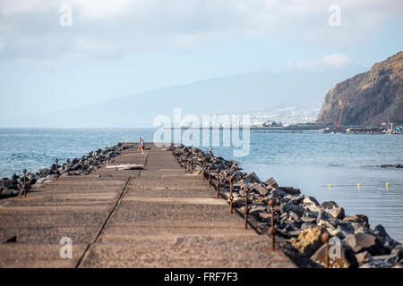 SANTA CRUZ, TENERIFE island, SPAIN - DECEMBER 23, 2015: Teresitas beach with stone padestrian road and city on the background in Stock Photo